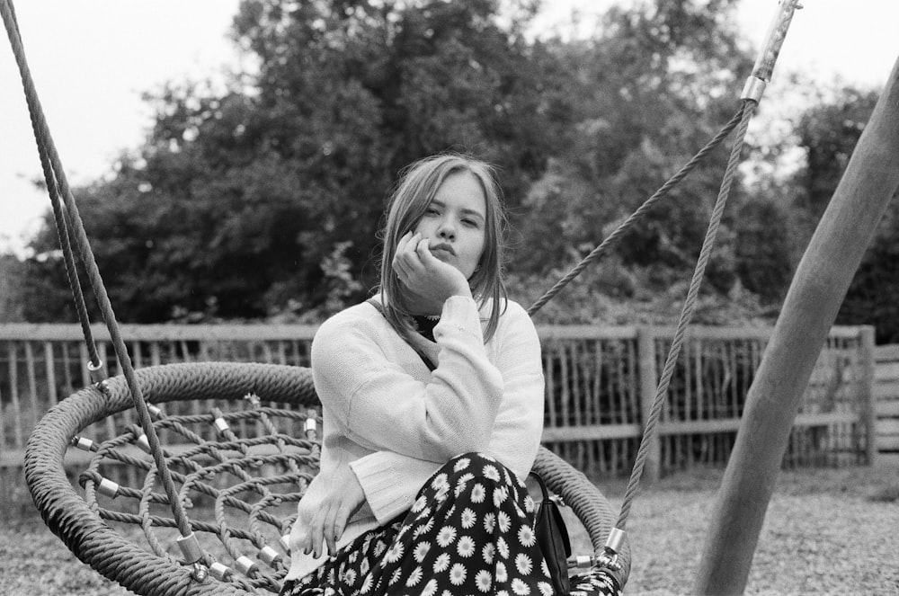 grayscale photo of woman on swing