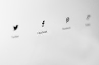 Logos of social media platforms are displayed in a minimalist style on a light gray background. The logos are aligned horizontally, and each is labeled with the name of the corresponding platform.