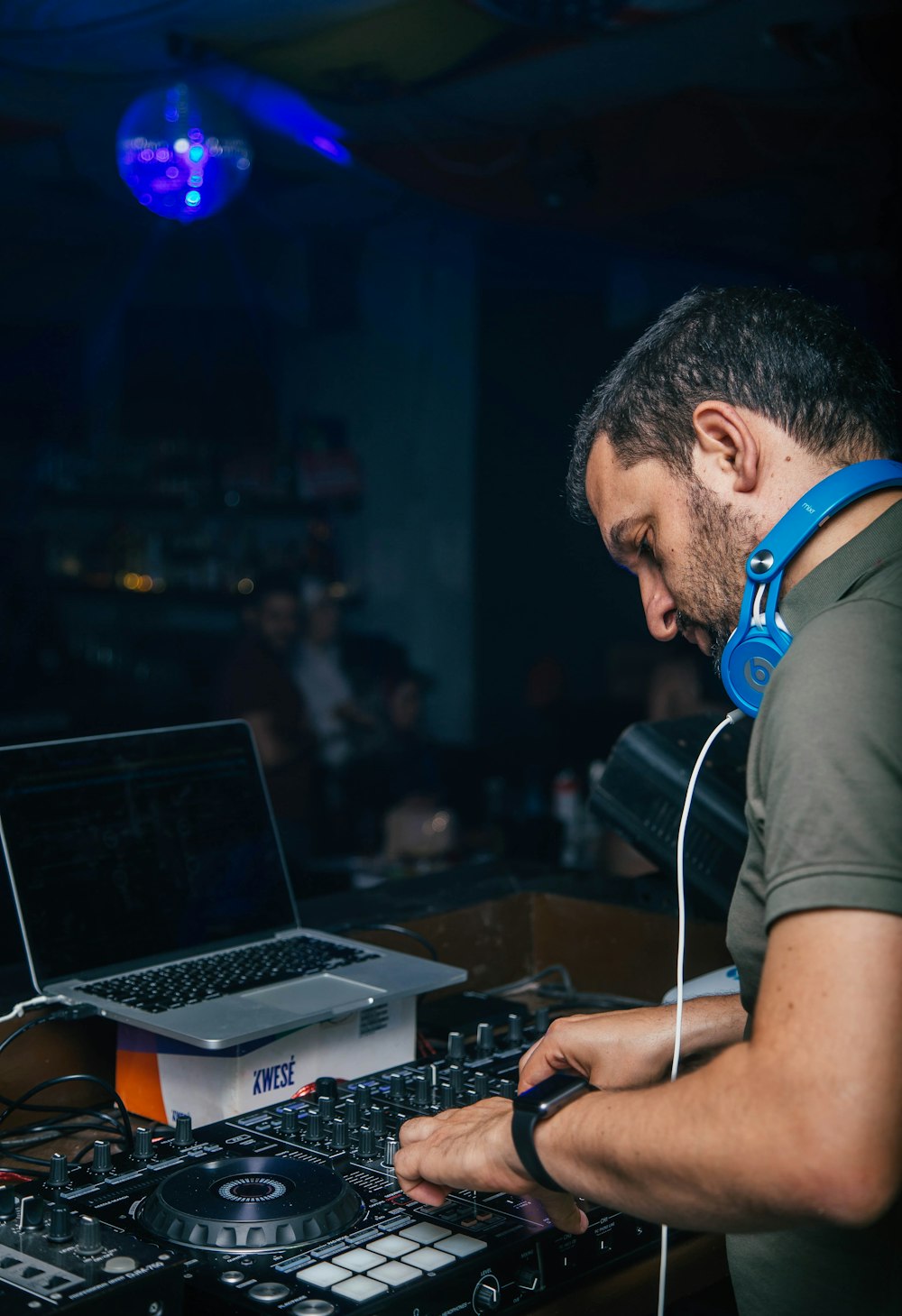 man wearing blue headphones while operating DJ controller