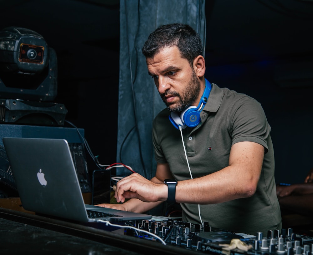 man wearing blue headphones and using MacBook