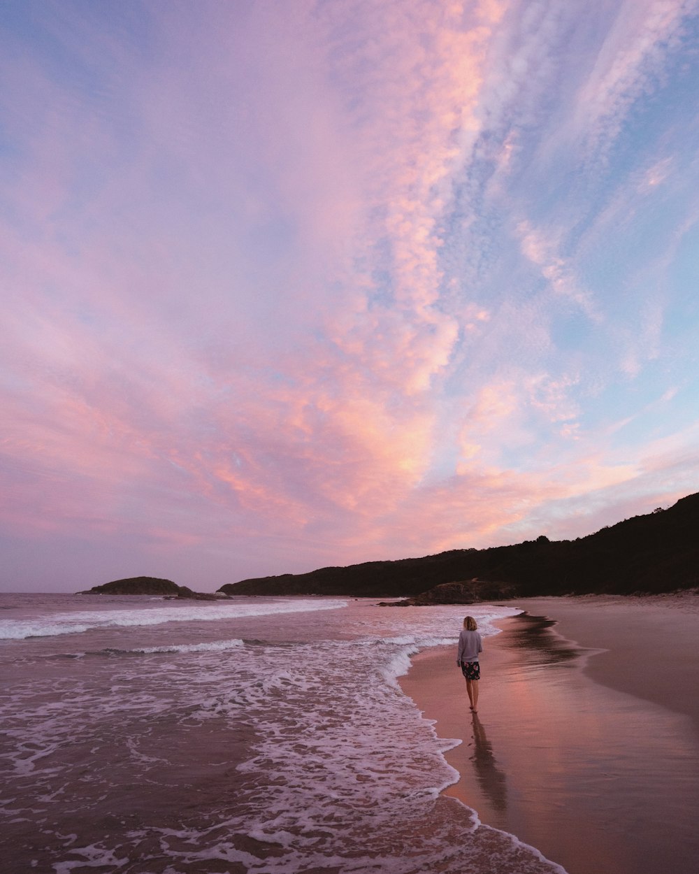 person walking on seashore during day