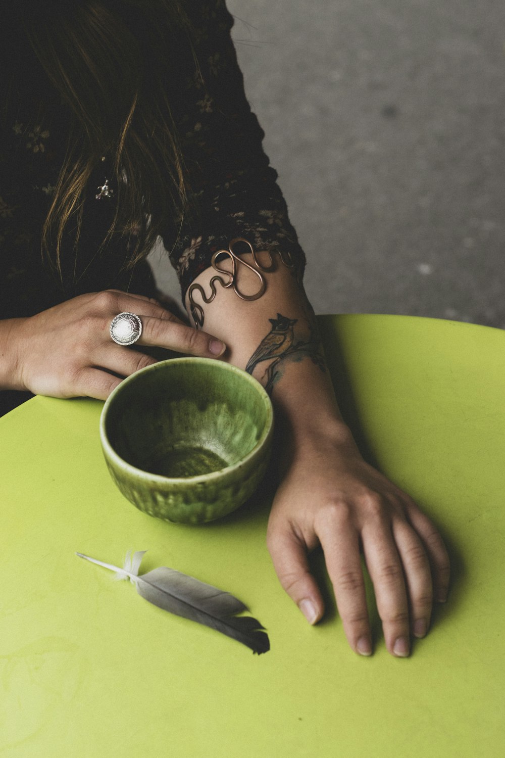a woman sitting at a table with a green bowl