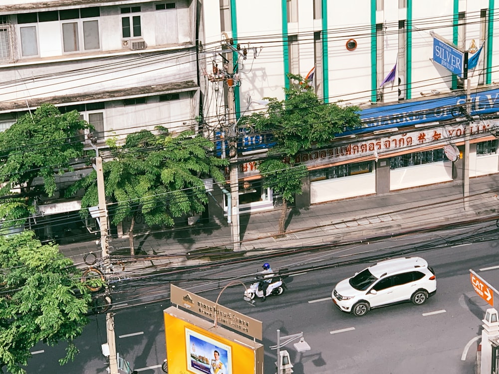 a white car driving down a street next to tall buildings