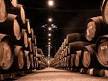 Barrel aging room with rows of wooden casks in soft lighting.