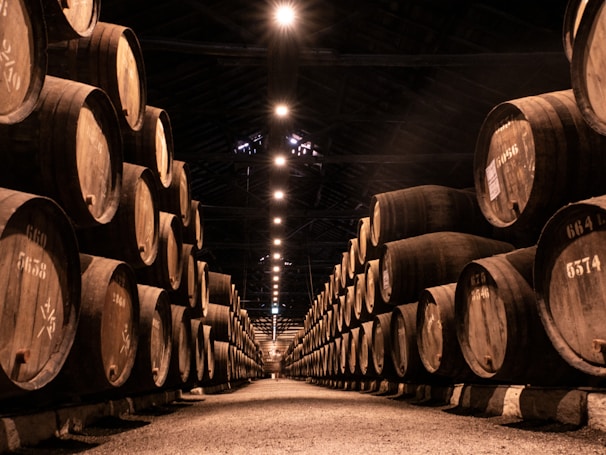Organized rows of beer cartons on pallets beneath strong industrial lighting in a dark-themed warehouse.