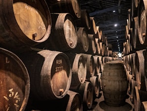 Artisanal oak barrels lined up in a dimly lit cellar, hinting at the aging process