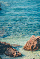 Crystal-clear turquoise waters gently lapping against the rocky coastline near Siracusa.