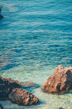 Crystal-clear turquoise waters gently lapping against the rocky coastline near Siracusa.