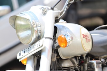 Close-up view of a motorcycle's front side, prominently featuring the headlight, turn signal, and part of the fuel tank with Royal Enfield branding.