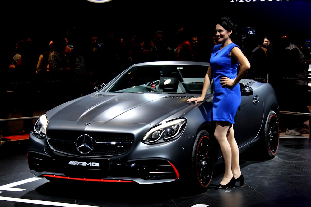 woman standing near Mercedes-Benz AMG convertible coupe