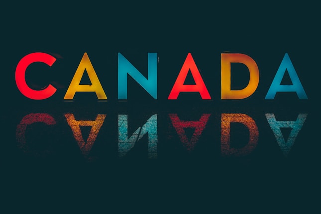 Illuminated letters spelling 'CANADA' with reflections on a dark background, symbolizing Canada