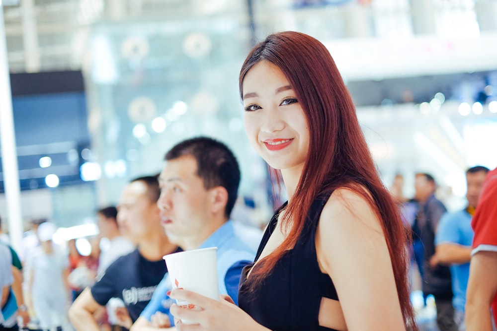 Fotografía de enfoque selectivo de mujer sonriente sosteniendo una taza blanca