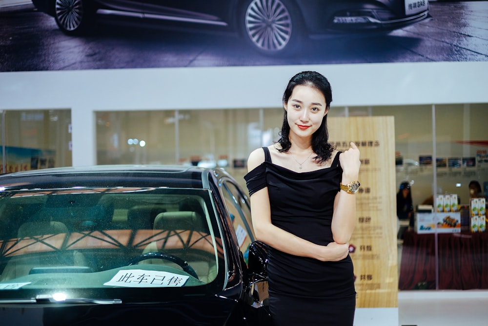 woman stands near black car