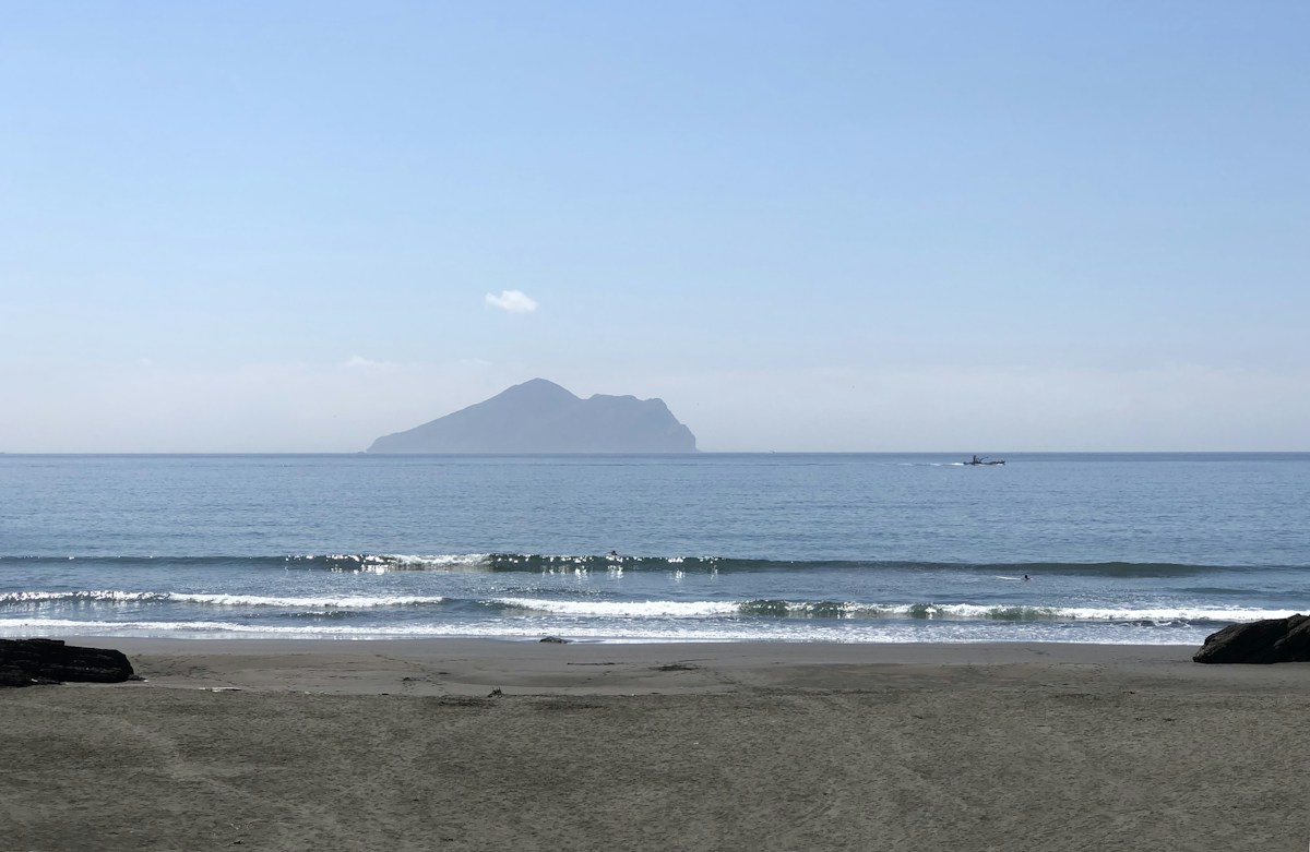 頭城濱海路旁的沙灘，遠方海面上是龜山島