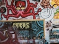 A vibrant mural featuring a red octopus with flaming yellow eyes, tentacles spread across the wall, surrounded by various graffiti elements and whimsical drawings. Below the mural, a coffee shop counter is visible with equipment like a coffee grinder and espresso machine, alongside cups and jars.