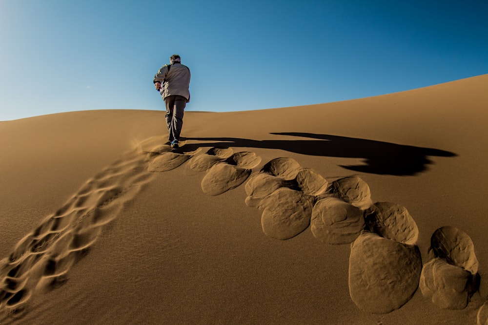 man waking on brown sand dunes