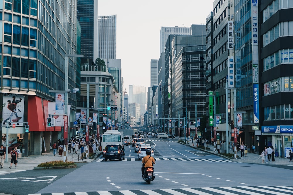 people and cars on road near buildings