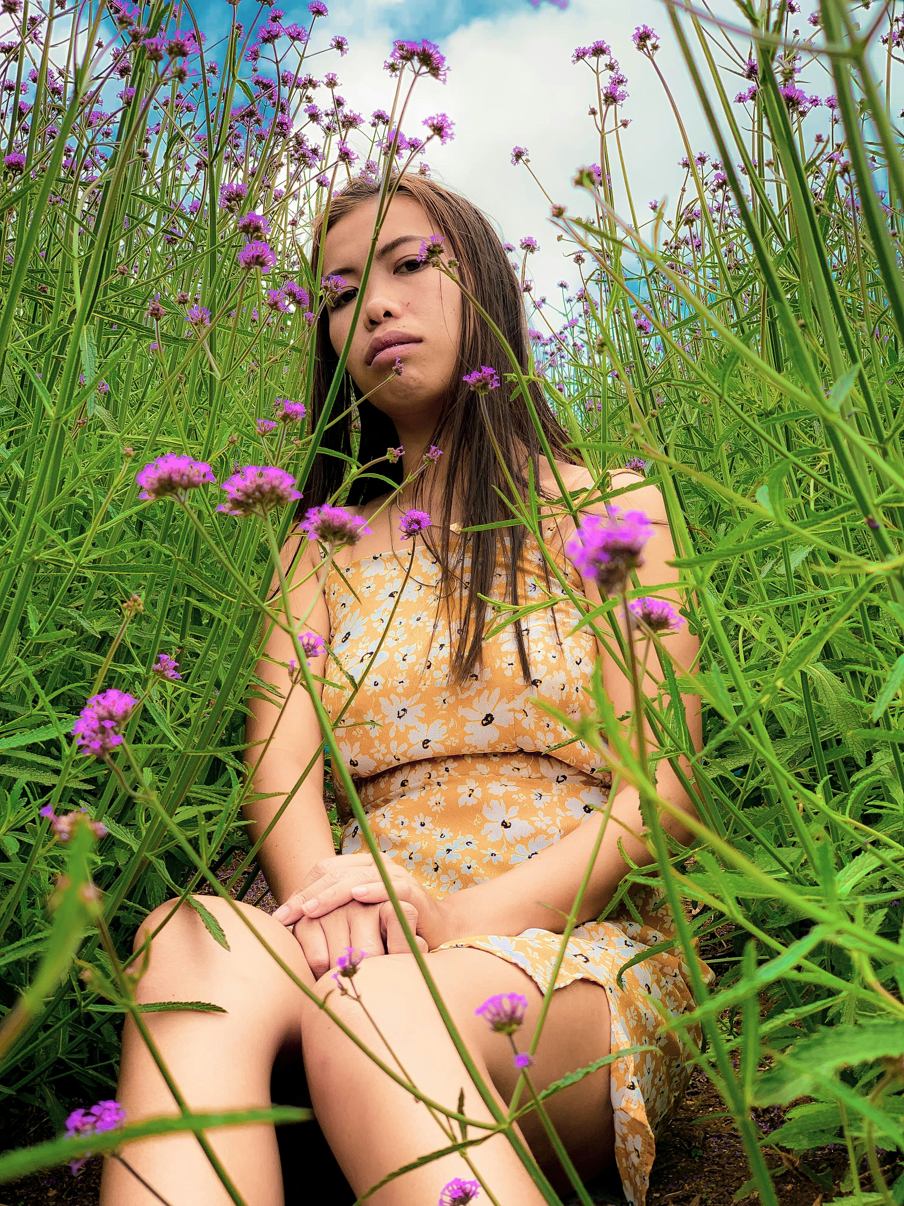 woman sitting on ground surrounded by purple-petaled flowers