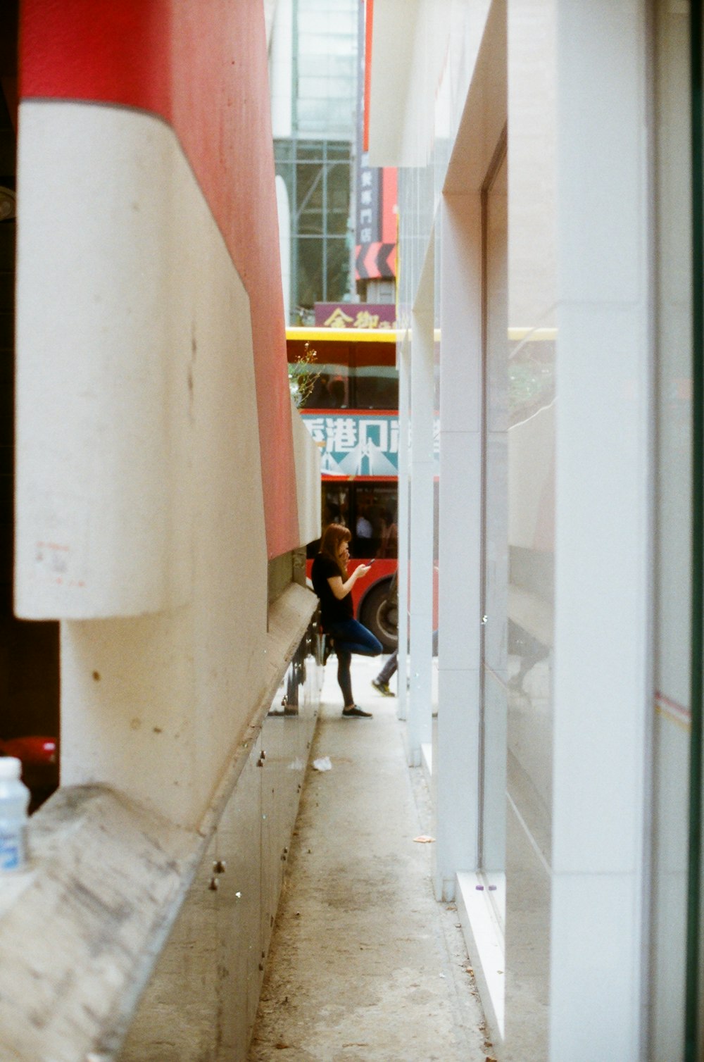 woman using phone while standing and leaning against the wall