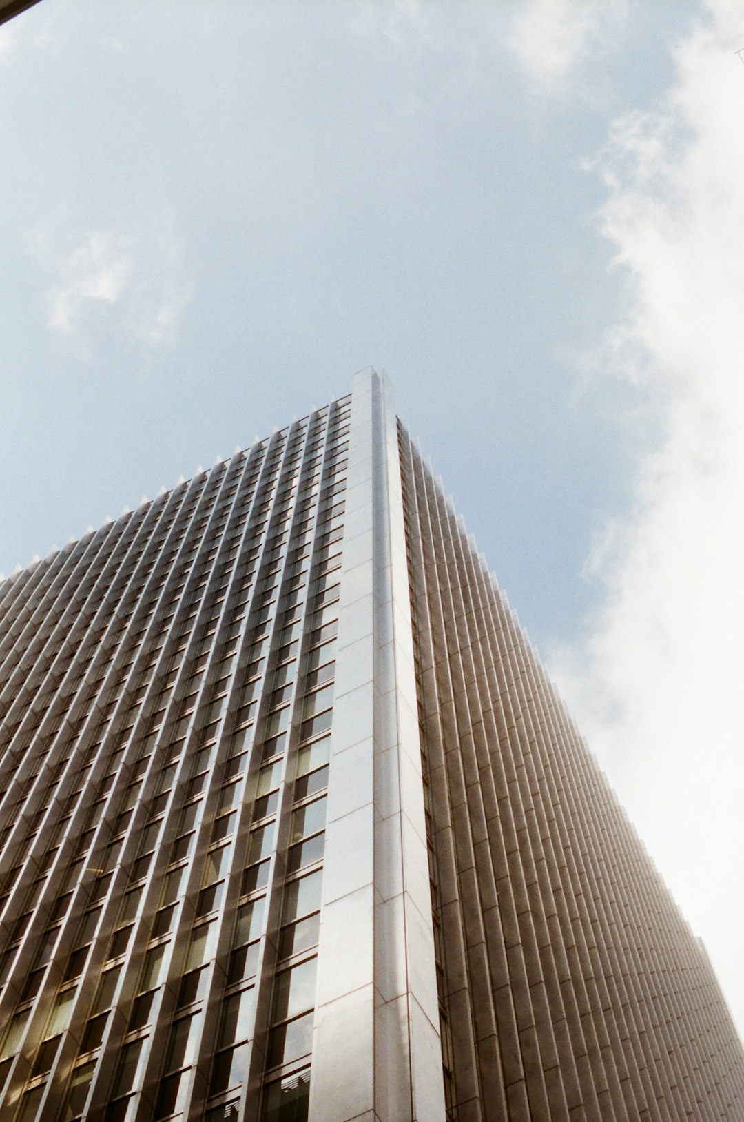 low-angle photography of brown high-rise building under blue and white skies during daytime