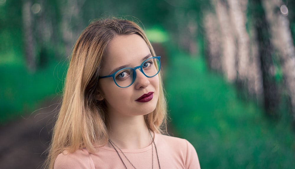 shallow focus photo of woman wearing eyeglasses with blue frames