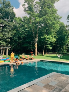 A sparkling, newly installed backyard pool with a sleek spa, surrounded by lush greenery and happy family enjoying the space.