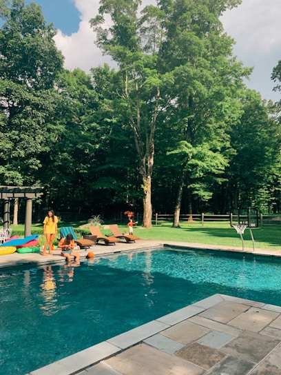 A sparkling, newly installed backyard pool with a sleek spa, surrounded by lush greenery and happy family enjoying the space.