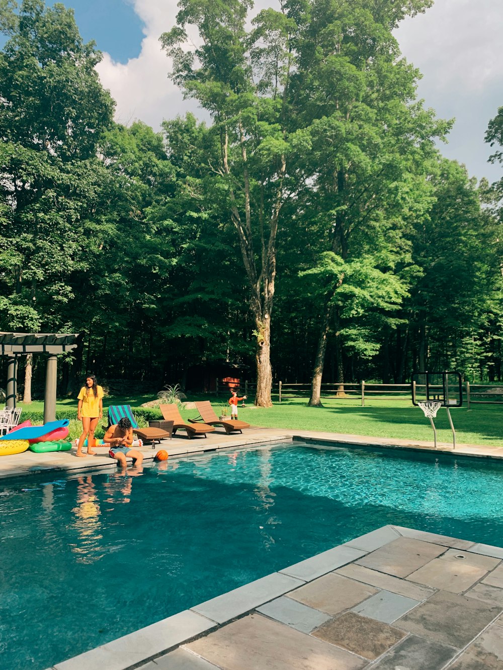 topless man sitting near swimming beside woman standing during daytime