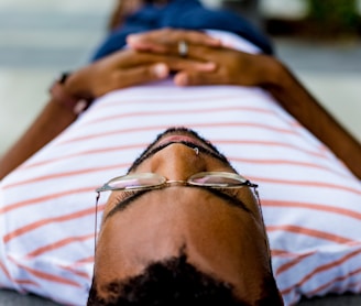 man wearing eyeglasses lying on concrete pavement