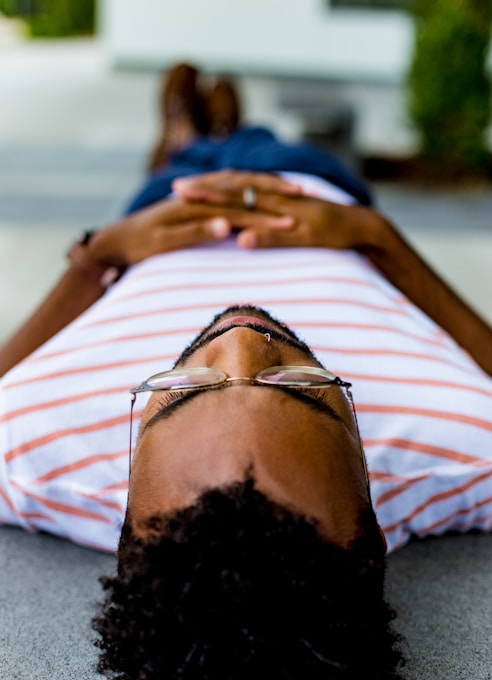 man wearing eyeglasses lying on concrete pavement