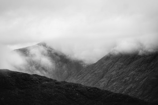 Black and white photograph of a misty mountain landscape at dawn.