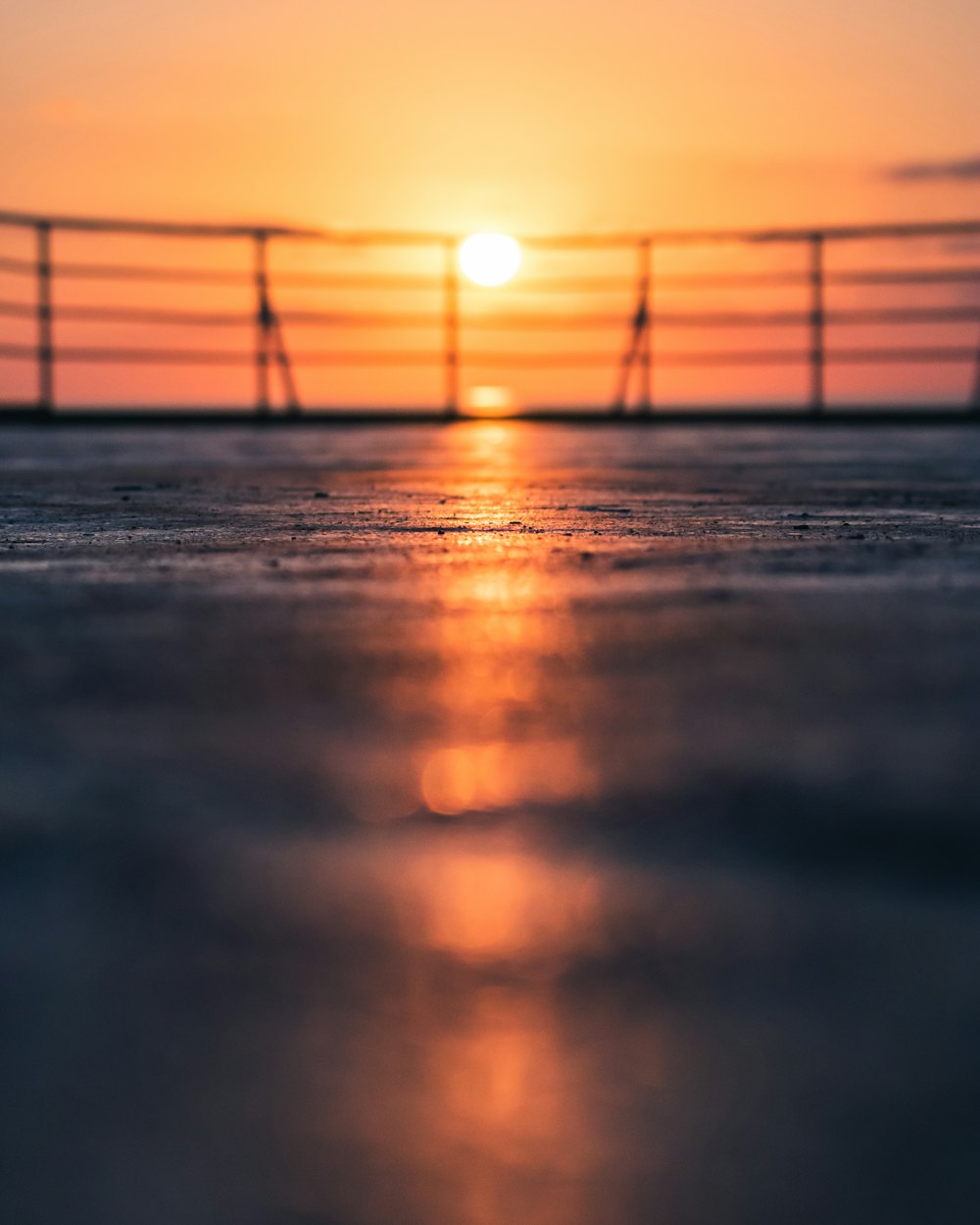 the sun is setting over the ocean with a bridge in the background