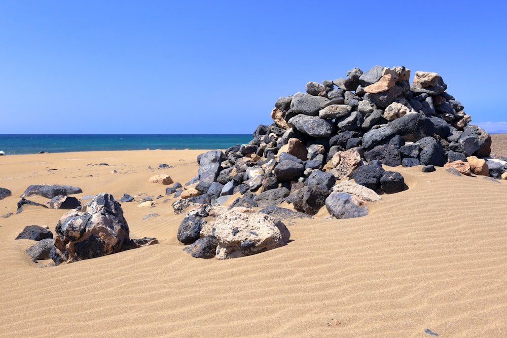 a pile of rocks sitting on top of a sandy beach