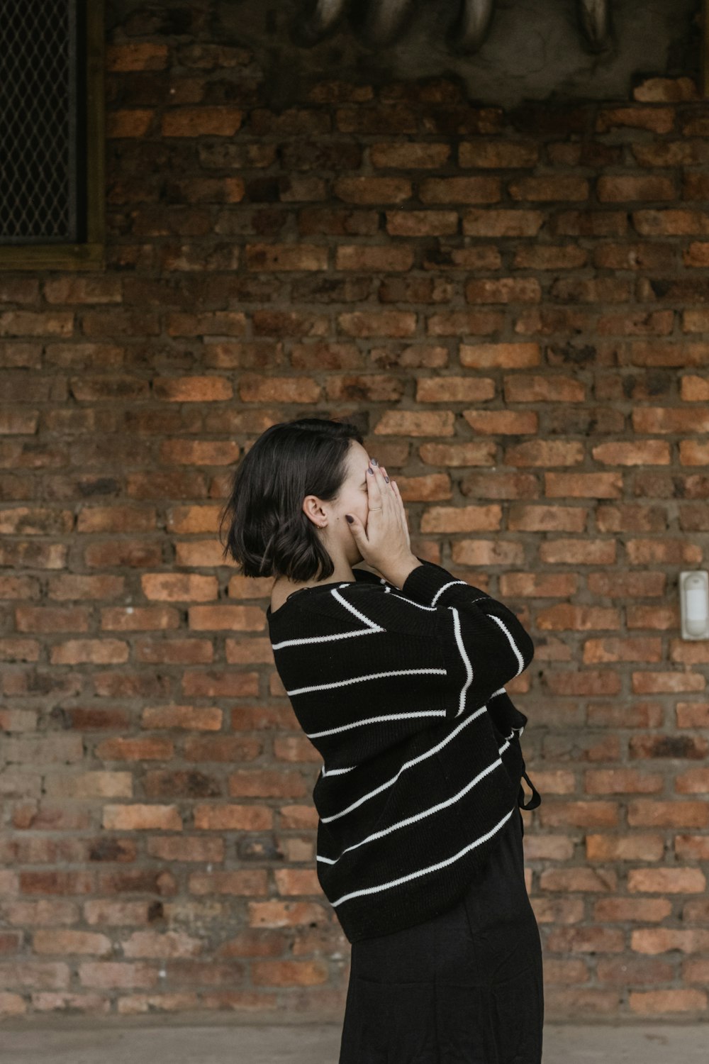 woman wearing black and white long-sleeved shirt covering her face