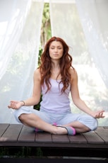 woman doing yoga pose sitting on wooden ground