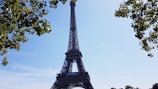The Eiffel Tower framed by blossoming spring trees under a clear blue sky.