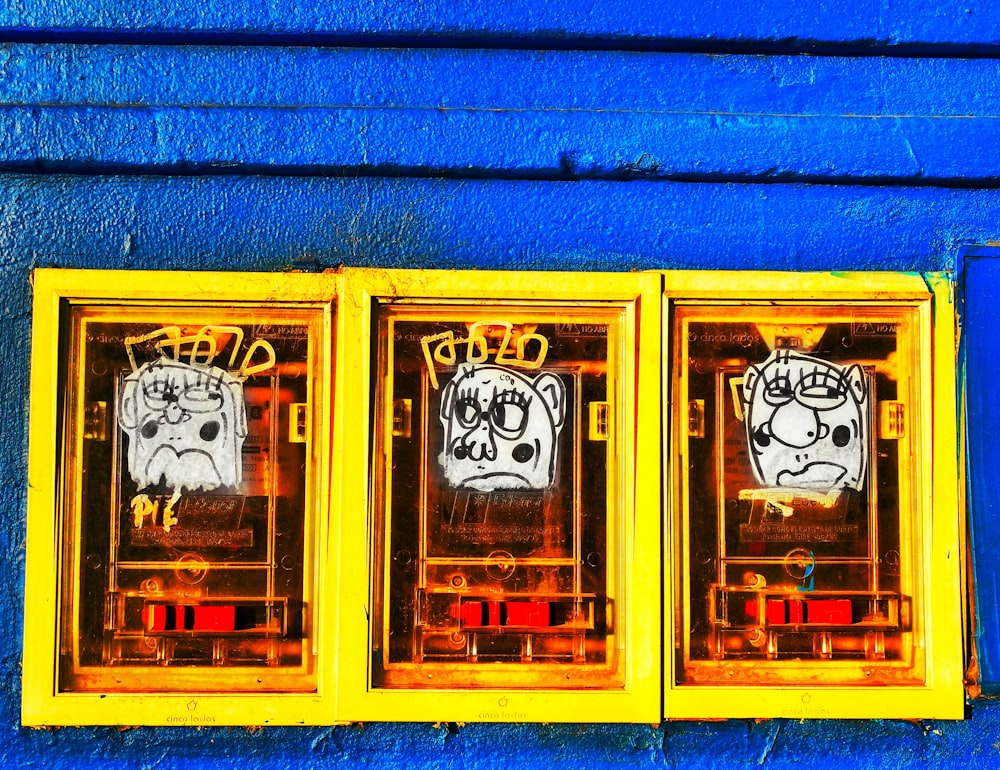 uma parede azul com três janelas com rostos desenhados sobre elas