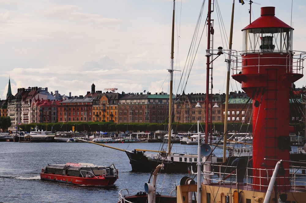 red boat on body of water besides ships