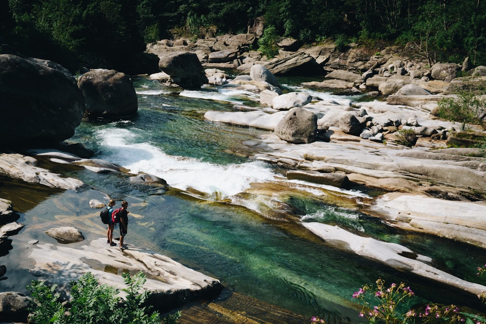 zwei Personen, die auf einem Felsen am Fluss stehen