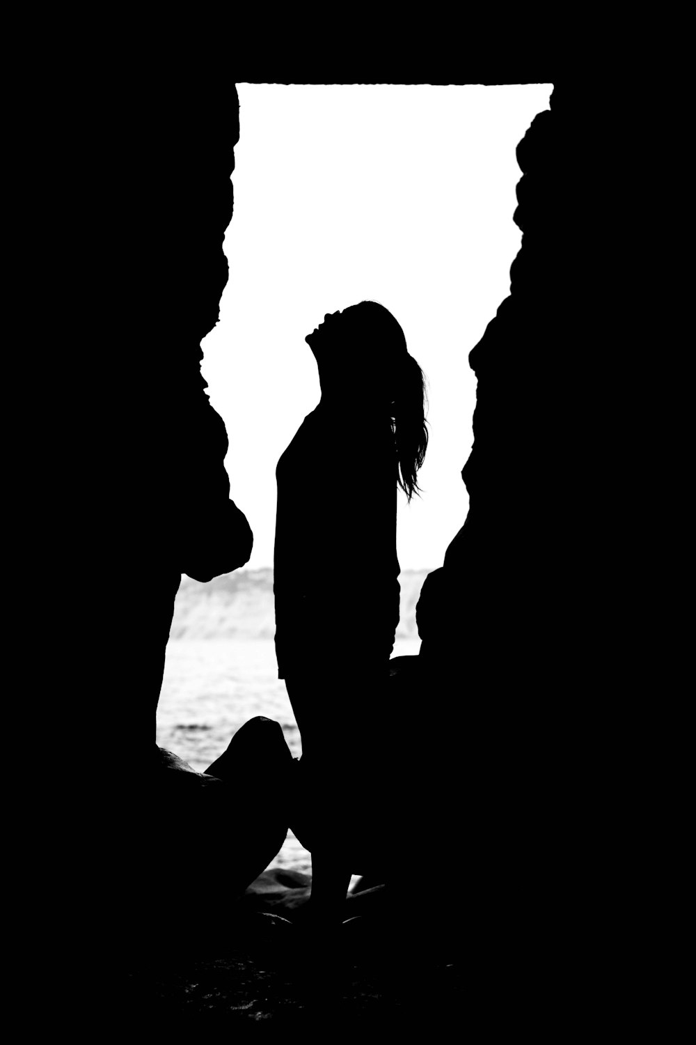 silhouette of woman looking up inside cave