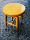 A proud DIYer holding a freshly painted wooden stool in a cozy workshop.