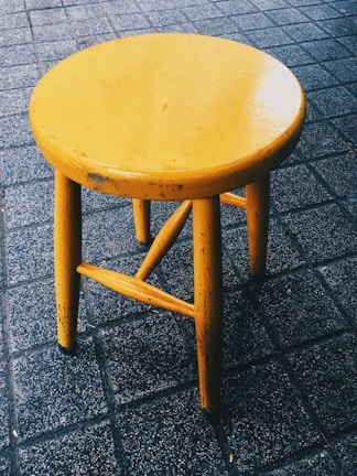 A proud DIYer holding a freshly painted wooden stool in a cozy workshop.