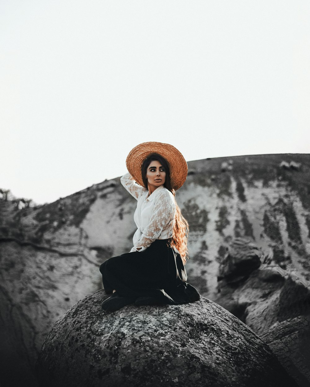 women wearing brown bat sitting on rock during daytime