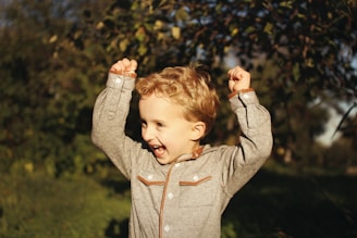 Close-up of a joyful toddler exploring nature outdoors, sunlight filtering through trees.