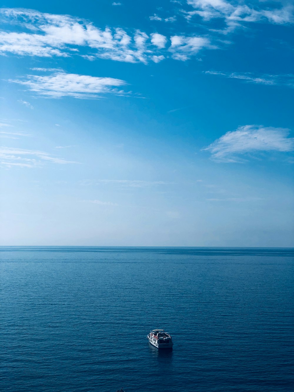 barco na água sob céu azul e nuvens brancas durante o dia