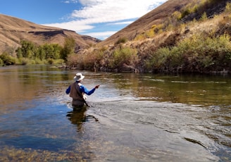 man wearing brown hat fishing on water