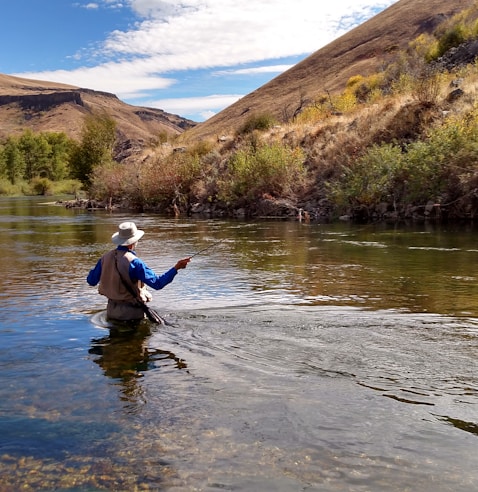 man wearing brown hat fishing on water