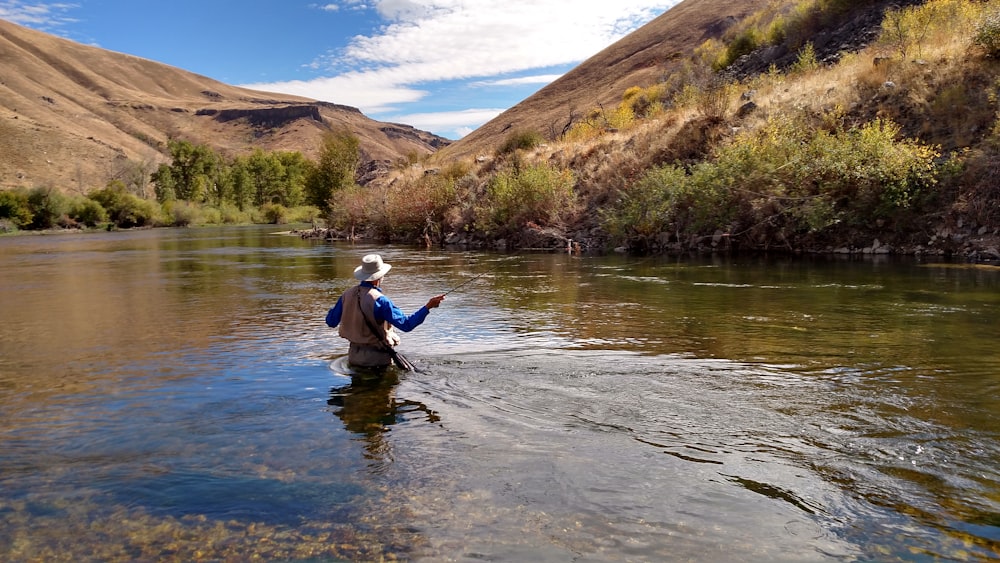 man wearing brown hat fishing on water