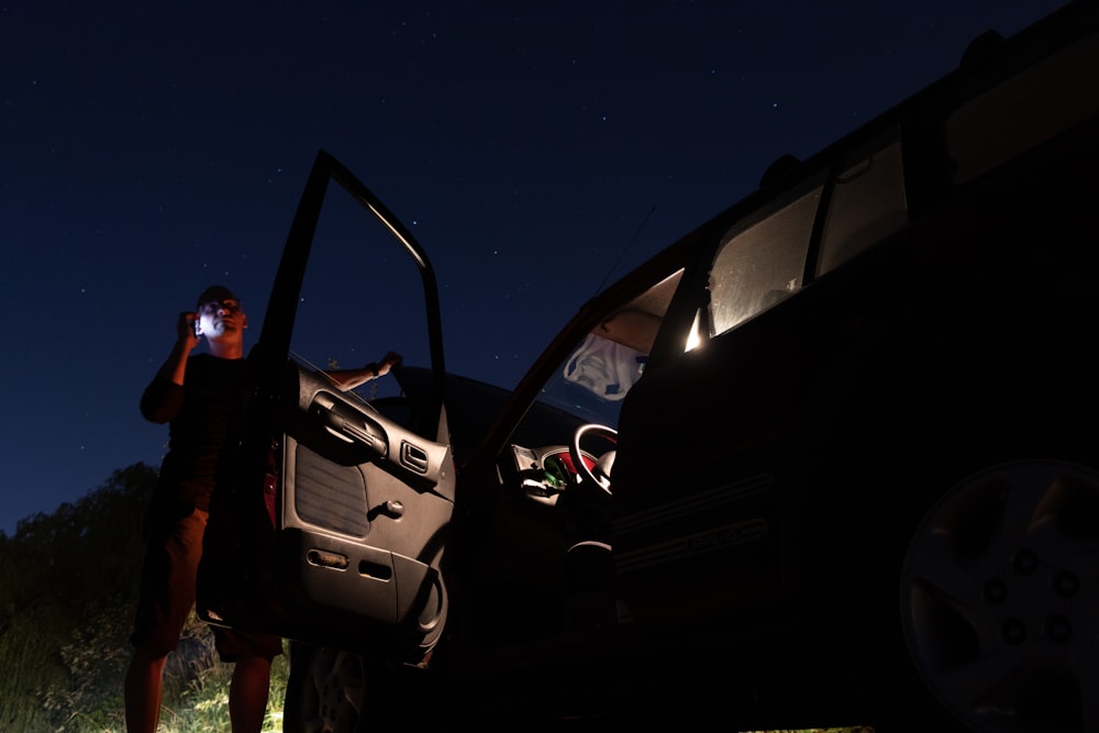 man beside parked car during night