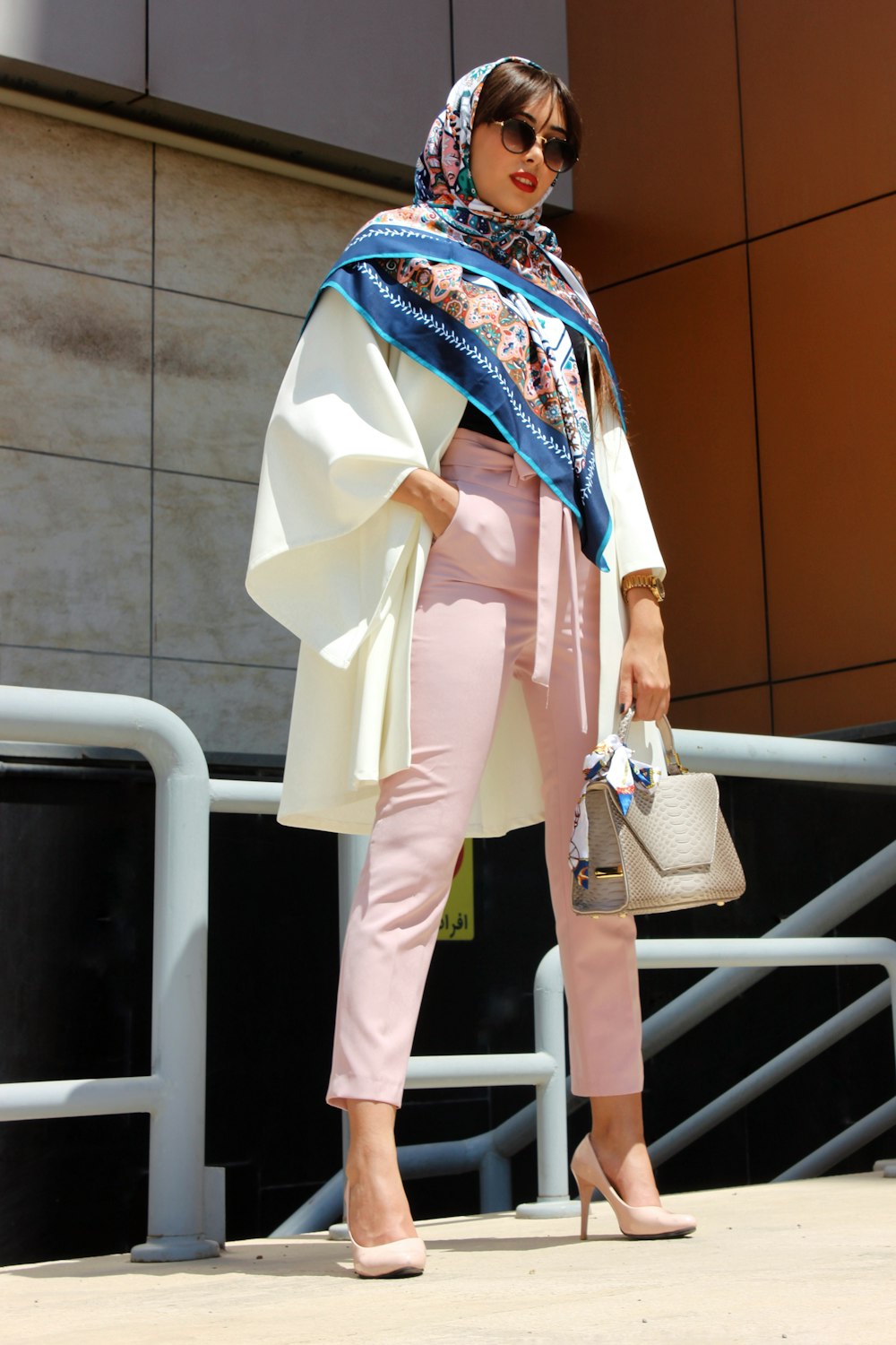 Mujer con pantalones rosas sosteniendo un bolso de cuero gris